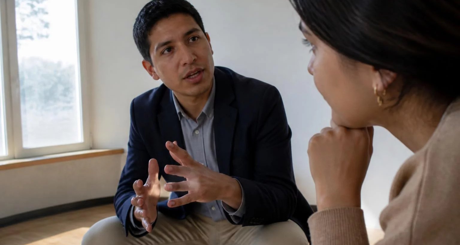 Dos personas conversando de cerca en una sala clara