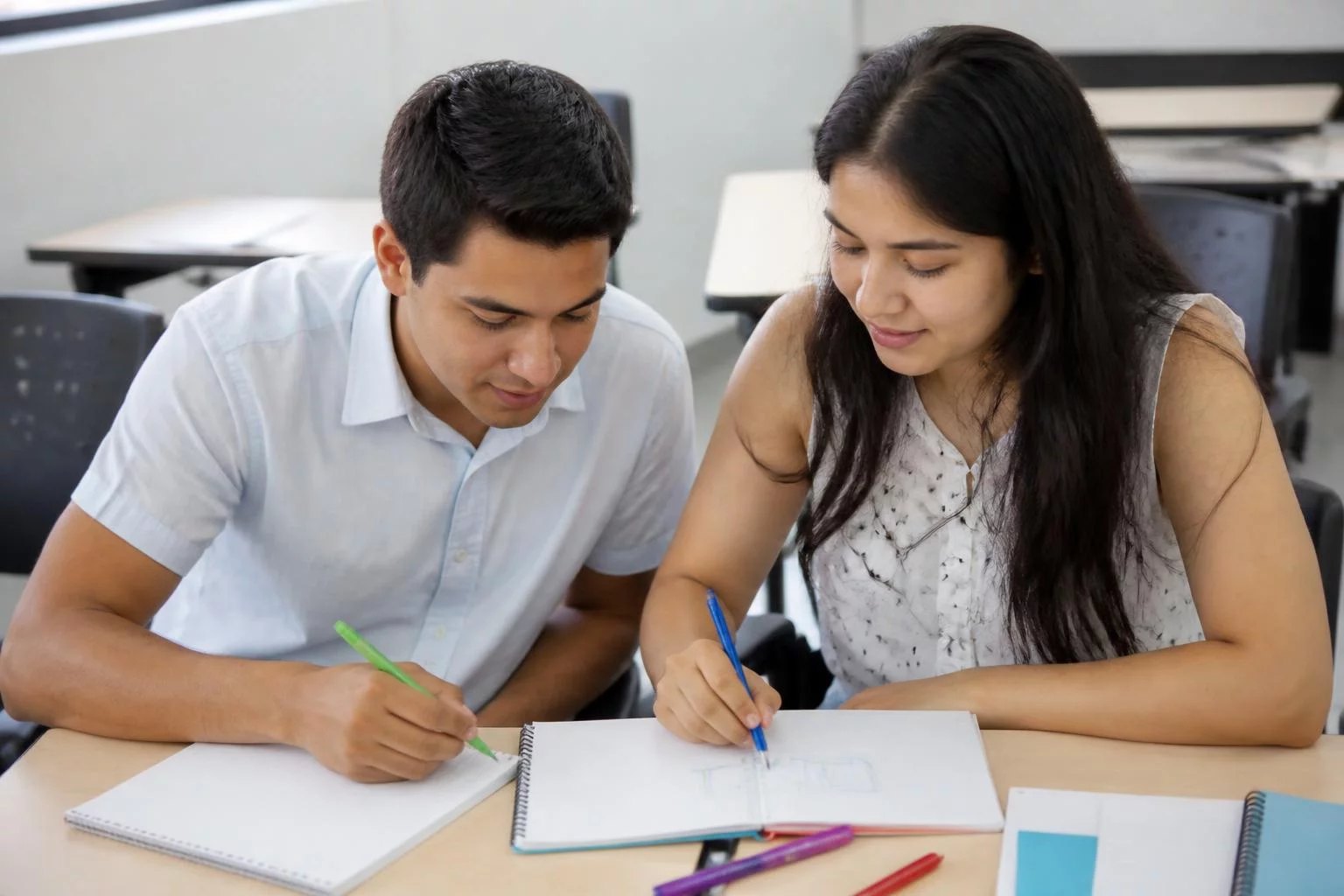 Dos personas preparando la ronda con cuadernos y plumones de colores